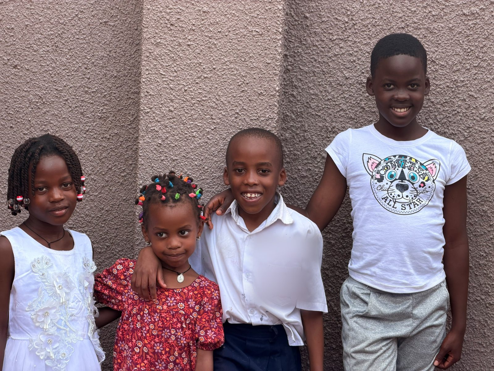 The four students in the first cohort, standing together against a wall in Uganda.